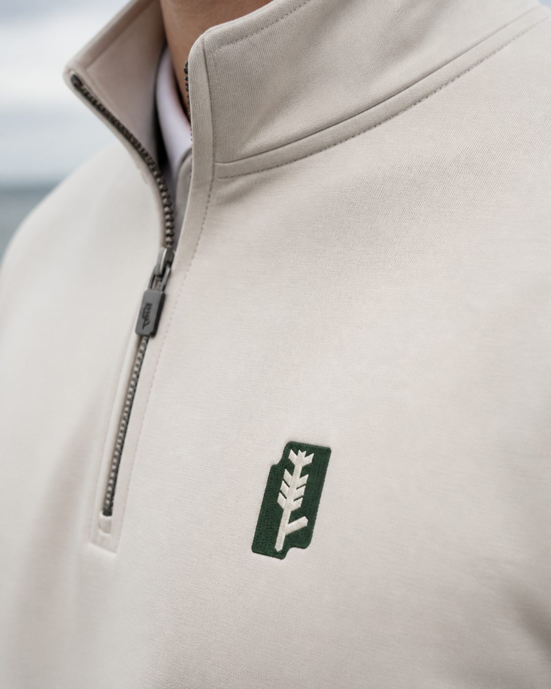A BUA quarter zip in Seabhac, the glyph embroidered on the chest in Verdantra green.
